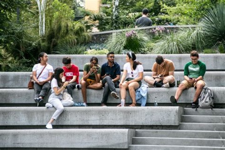 a group of people sitting at a table with plates and flowers in front