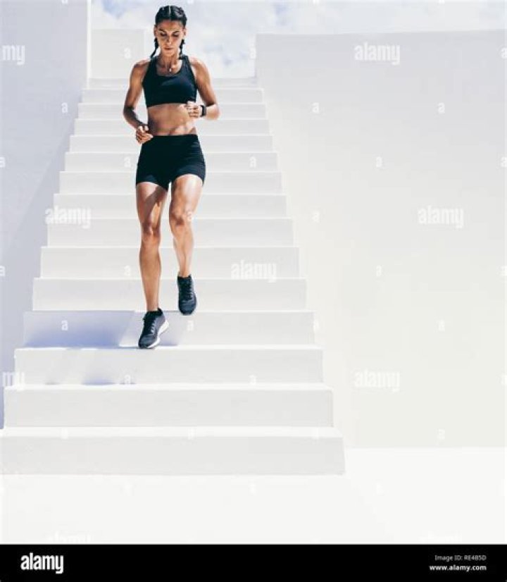 a woman running down the street wearing black shorts and a sports bra